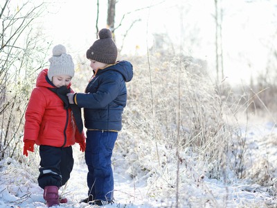 Två stycken barn leker i snön.