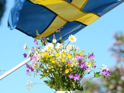 En bukett med blommor och en svensk flagga i bakgrunden
